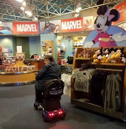 A woman riding her i3 mobility scooter while shopping at Disneyland.